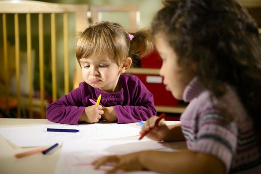 Children and fun, two preschoolers drawing in kindergarten