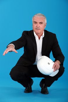 Grey haired architect crouching and offering to shake hand