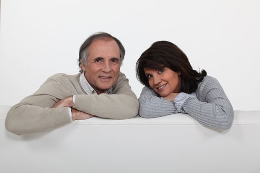 Couple leaning over the backrest of their couch