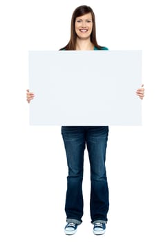 Trendy woman showing blank billboard to camera. Full length studio shot.