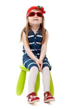 little girl in a red hat and sunglasses sitting on a green chair