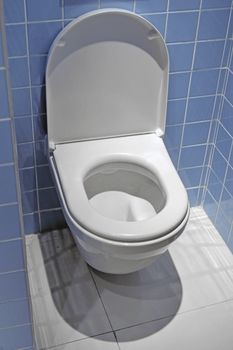 blue tiled room space and clean white toilet with open cover