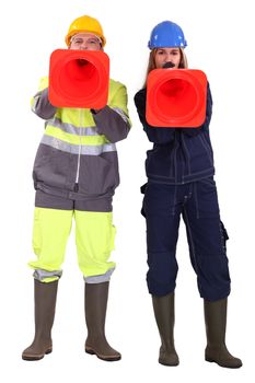 Two traffic workers shouting through cones