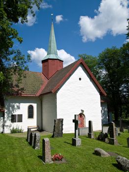 The medieval church at Haslum, a suburb of Oslo in Norway with the church yard in the foreground.