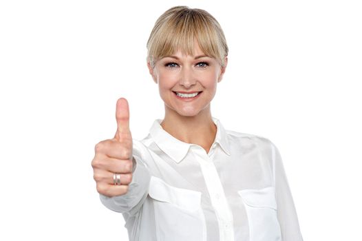 Blonde woman in formal attire showing thumbs up gesture