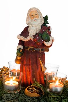 Advent wreath with burning red candles and Santa Claus figure in the centre