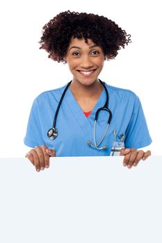 Joyous female doctor standing behind ad board