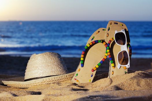 Wicker hat, sandal and glasses on the sandy beach
