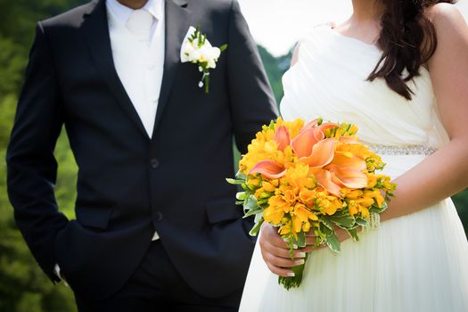 Young married couple holding hands with  wedding bouquet