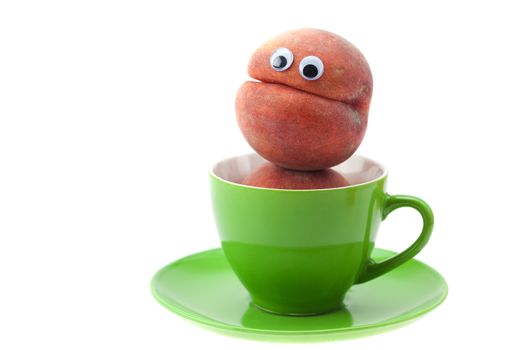 Peach with eyes in the cup and saucer isolated on white