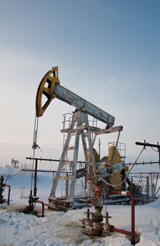Oil pumpjack against bright, blue winter sky. Russia, Western Siberia.