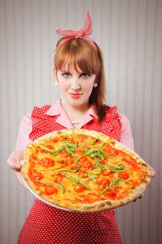 Young housewife holding a vegetarian pizza for lunch