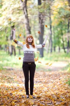 young redhead teenager throwing leaves woman in the forest  