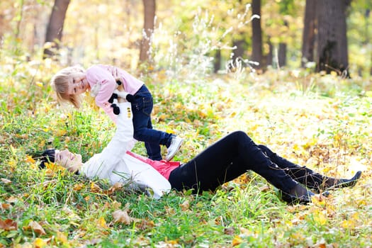beautiful young mother and her daughter lying on the autumn leav