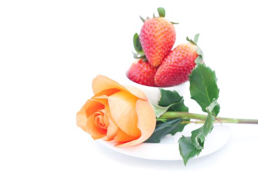 beautiful orange rose , strawberry and cup isolated on white