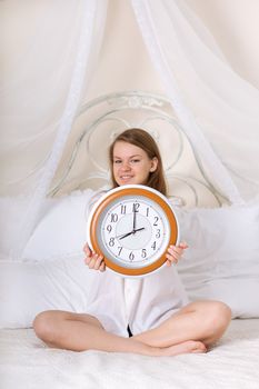 young woman in bed and alarm clock