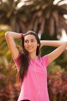 Young beautiful woman with sporty look enjoying with headphones outdoors