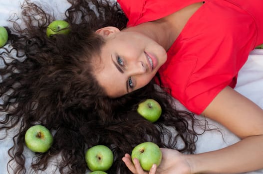 Woman lying in wheat field with green apple. Picnic.