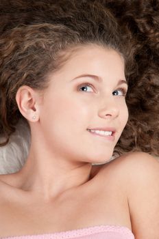 Girl with perfect curly hair lying on fur bed