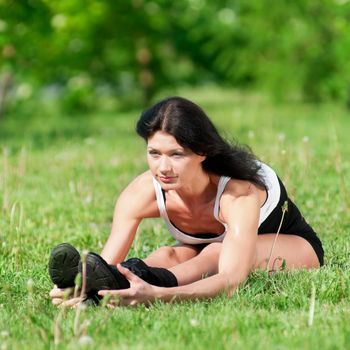 Athletic woman stretching her leg at the park