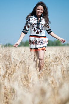 Beautiful woman walk in wheat field on sunny summer day.