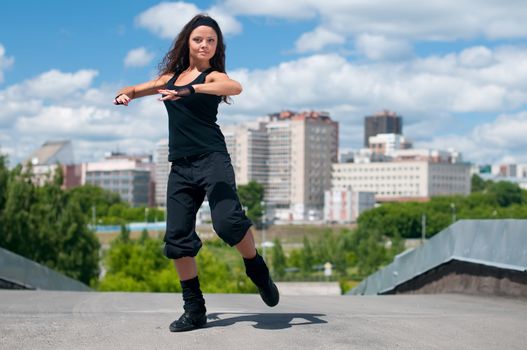 Beautiful girl dancing hip-hop over urban landscape