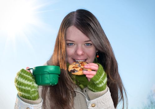 Girl on winter picnic with cup of tee and cookies