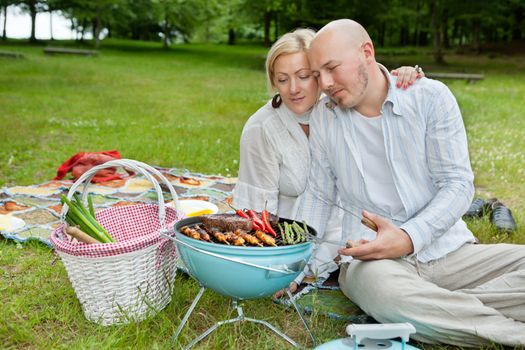 Mature Couple Cooking On An Outdoor Picnic