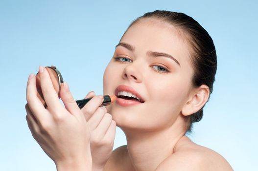 Beautiful young adult woman applying cosmetic lipstick