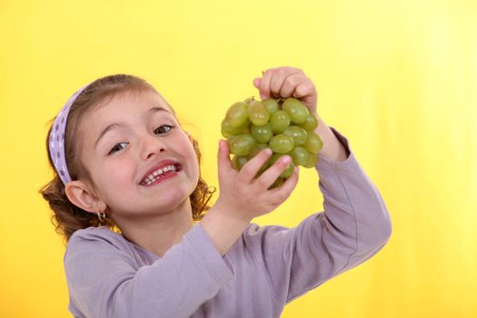 Little girl holding bunch of green grapes