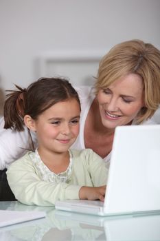 Mother and young daughter using a white laptop computer together