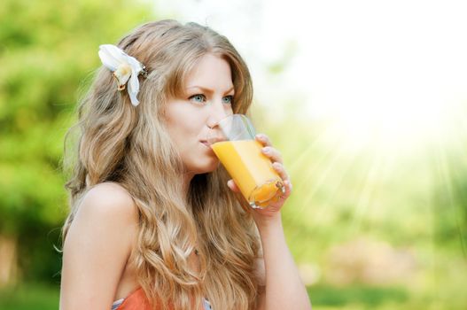 Young happy smiling woman drinking orange juice outdoor