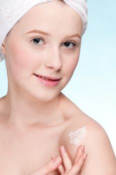 Beautiful woman applying moisturizer cream on face