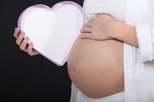 Pregnant woman holding heart shaped box