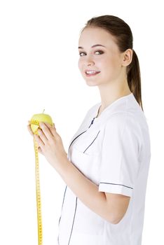 Smiling woman doctor with a green apple and measuring tape. 