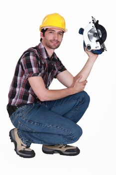 Man crouching down whilst holding circular saw