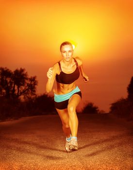 Sporty woman running on sunset