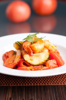 Thai style sweet and sour shrimp dish presented beautifully on a round white plate.