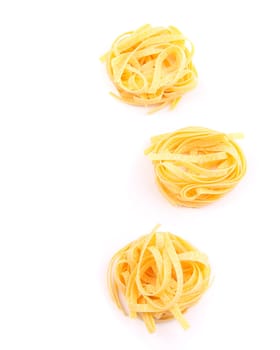 Three fettuccini pasta nests isolated on white.