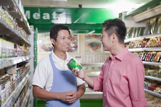 Sales clerk assisting man in supermarket, Beijing