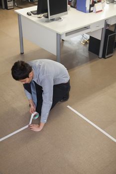 Young Businessman taping up the floor in the office