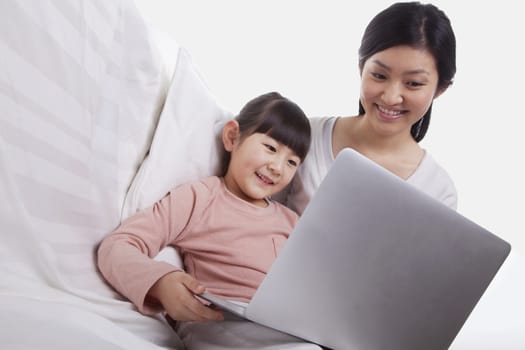 Mother and daughter sitting on sofa using a laptop, tilt