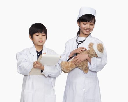 Boy and girl dressed up as doctors checking teddy bear's vital signs