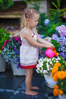 Little cute girl watering flowers with a watering can