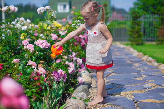 Adorable cute girl watering flowers with a watering can