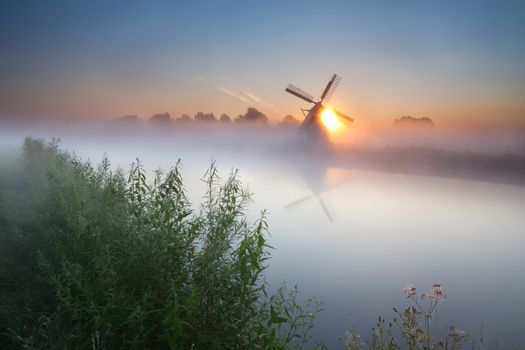 summer sunrise over river and windmill