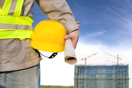 Construction building with worker holding hat 