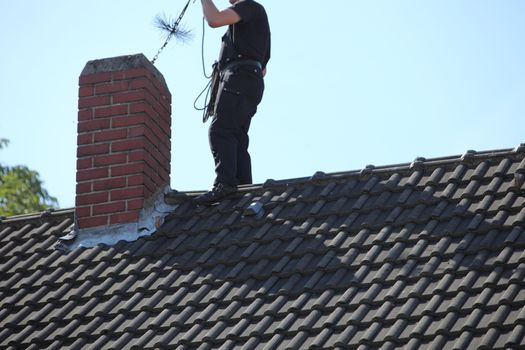 Chimney sweep at work on the roof
