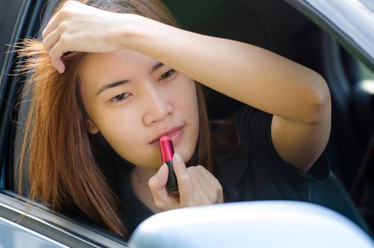 Asian girl applying makeup while in the car