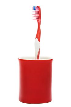  Toothbrush in a red glass on a white background